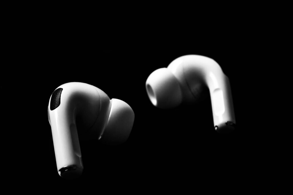 Sleek white earbuds isolated on a dramatic black background, emphasizing modern technology.